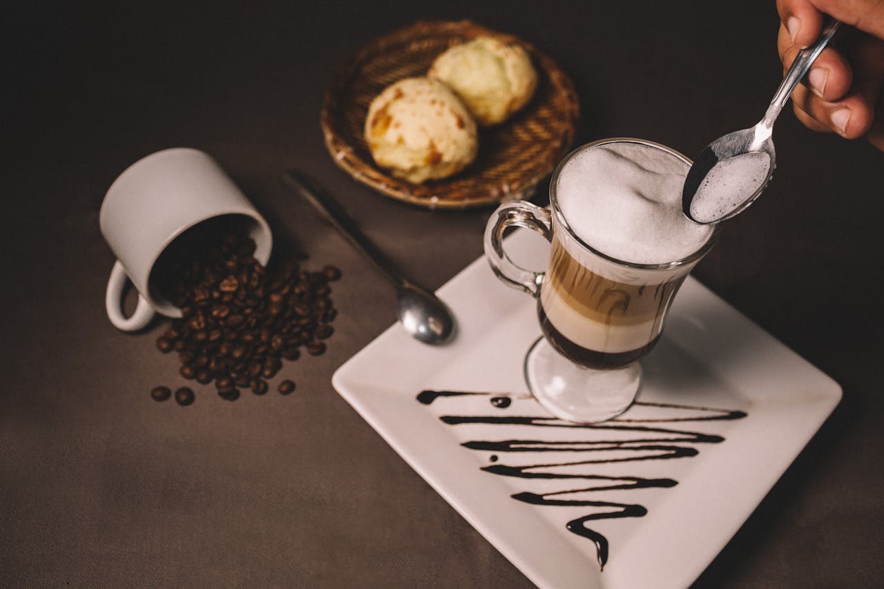 Elegant tabletop coffee setup with biscuits, coffee beans, and cream decoration.