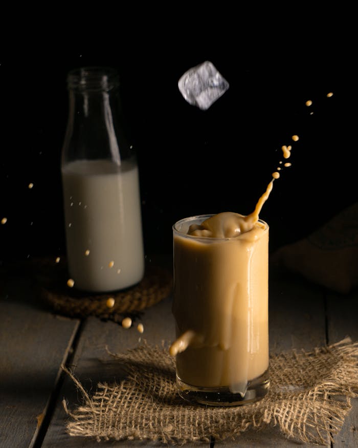 services-02 Captivating black background image of milk tea splash showcasing ice cube motion and milk in the background.